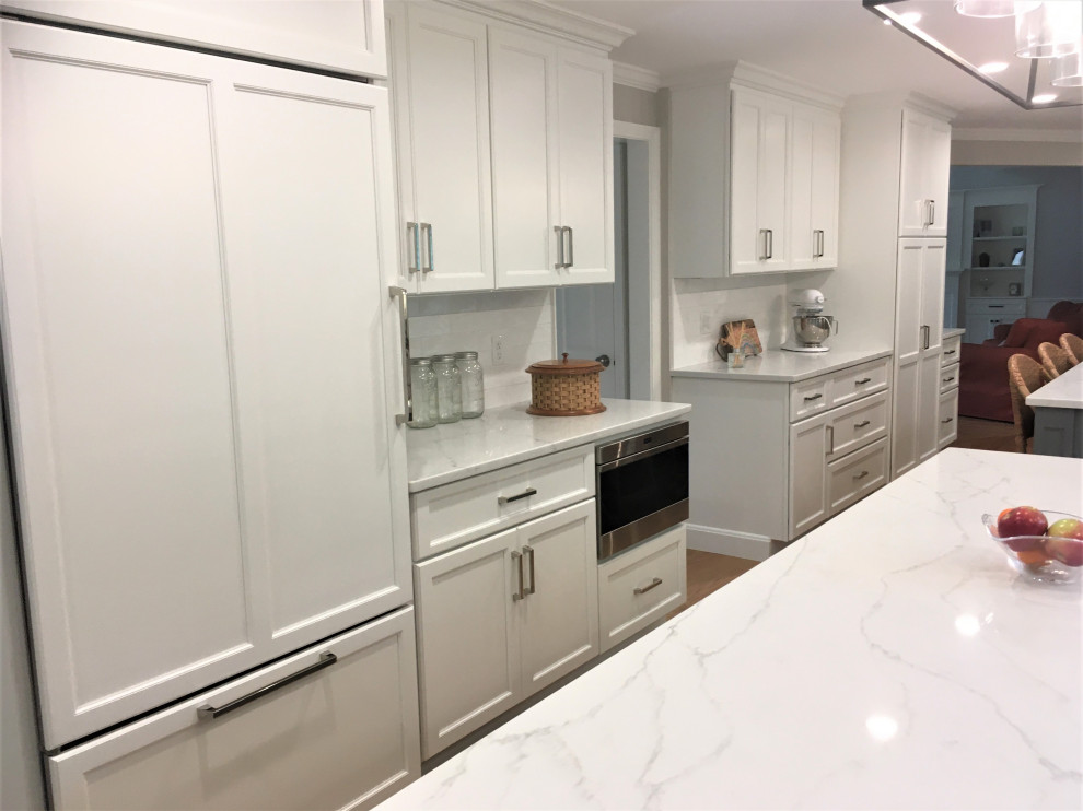 Large transitional galley light wood floor and brown floor eat-in kitchen photo in Boston with an undermount sink, shaker cabinets, white cabinets, quartz countertops, white backsplash, subway tile backsplash, stainless steel appliances, two islands and white countertops