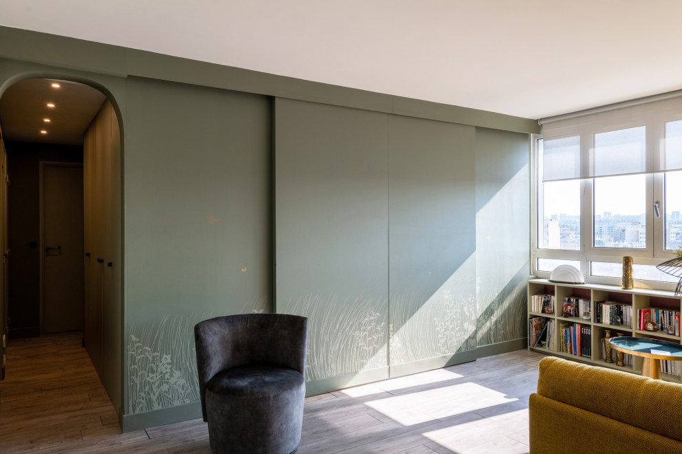Exempel på ett litet modernt allrum med öppen planlösning, med ett bibliotek, gröna väggar, ljust trägolv och brunt golv