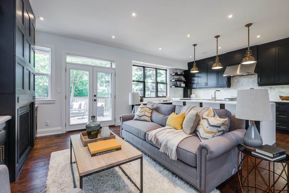 Inspiration for a mid-sized transitional open concept living room in Toronto with grey walls, a standard fireplace, a wood fireplace surround, a wall-mounted tv and medium hardwood floors.