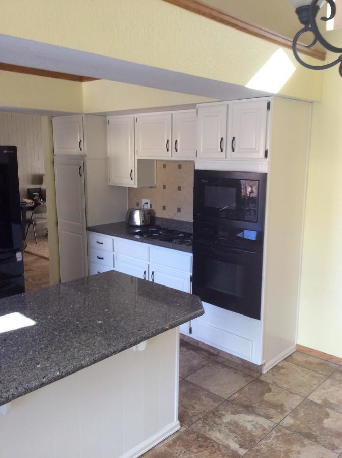 Eat-in kitchen - mid-sized transitional l-shaped ceramic tile eat-in kitchen idea in Denver with raised-panel cabinets, white cabinets, granite countertops, beige backsplash and a peninsula