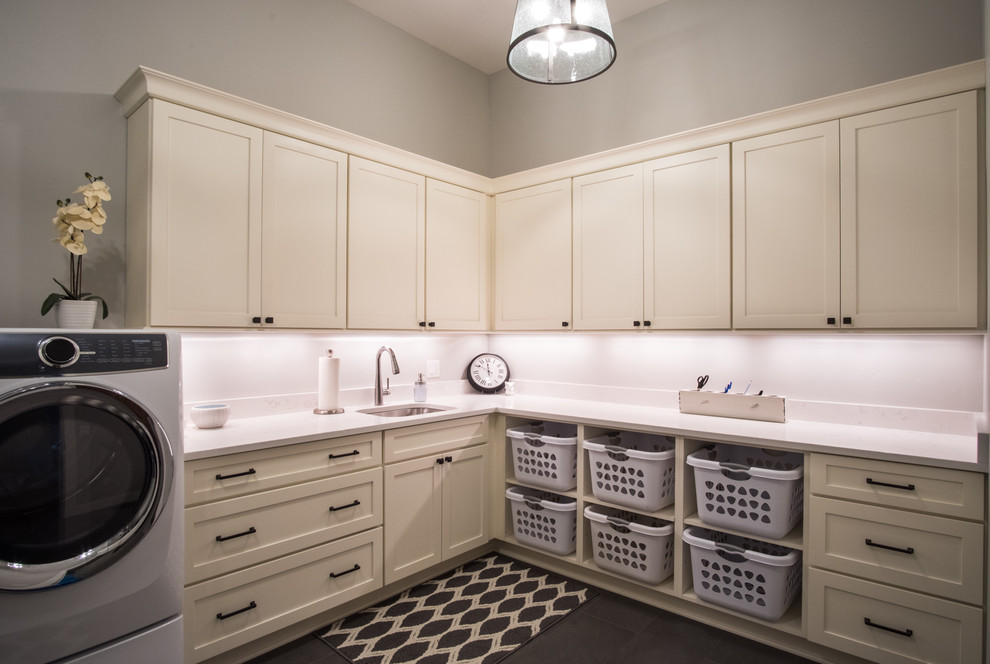 This is an example of a large transitional l-shaped dedicated laundry room in Portland with an undermount sink, shaker cabinets, white cabinets, quartz benchtops, grey walls, slate floors, a side-by-side washer and dryer, grey floor and white benchtop.