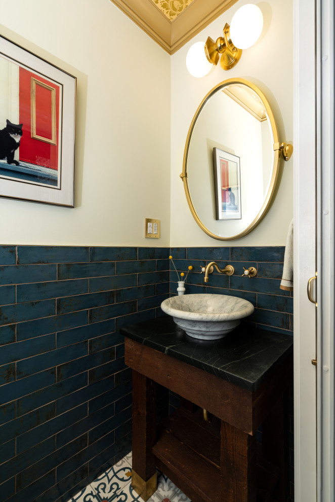 Powder room in Wilmington with open cabinets, dark wood cabinets, blue tile, a freestanding vanity, wallpaper and a vessel sink.