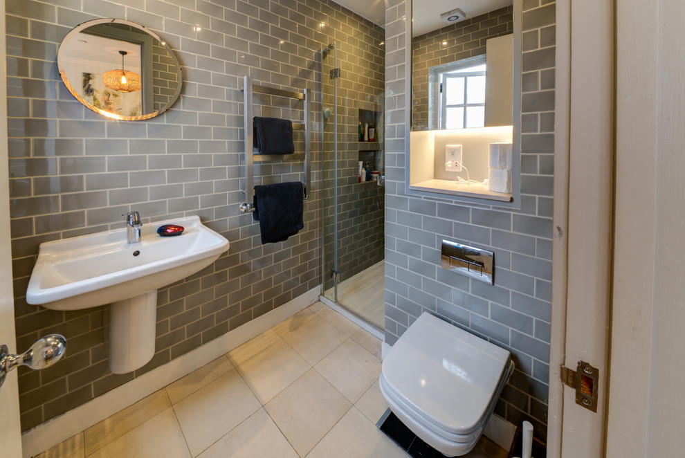This is an example of a mid-sized modern master wet room bathroom in London with recessed-panel cabinets, white cabinets, a wall-mount toilet, gray tile, ceramic tile, grey walls, travertine floors, a wall-mount sink, beige floor and a hinged shower door.