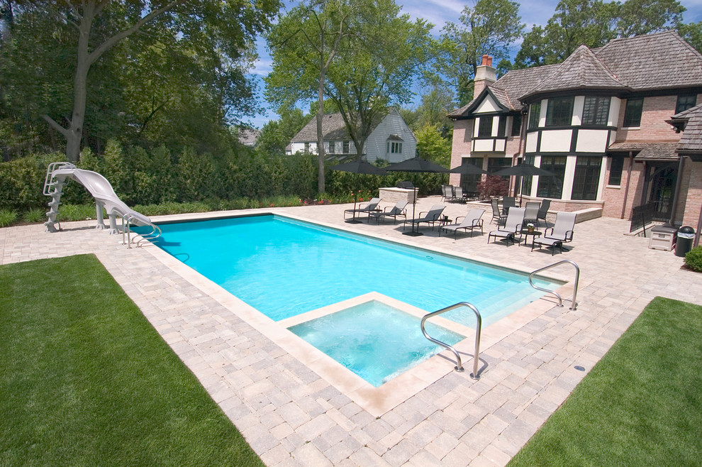 Small traditional backyard rectangular lap pool in Chicago with a water slide, a hot tub and concrete pavers.