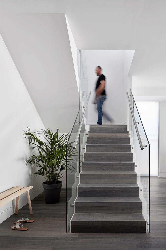 This is an example of a small contemporary wood u-shaped staircase in Melbourne with wood risers and glass railing.