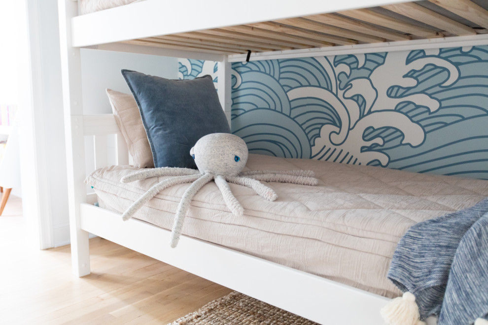 Photo of a large beach style gender-neutral kids' bedroom for kids 4-10 years old in Other with blue walls, light hardwood floors and wallpaper.