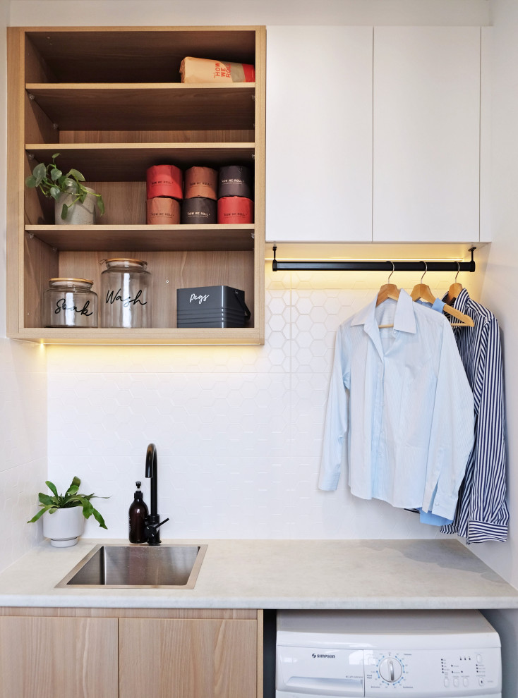 Example of a small danish single-wall utility room design in Geelong with an utility sink, open cabinets, white cabinets, laminate countertops, white backsplash, ceramic backsplash, white walls and white countertops