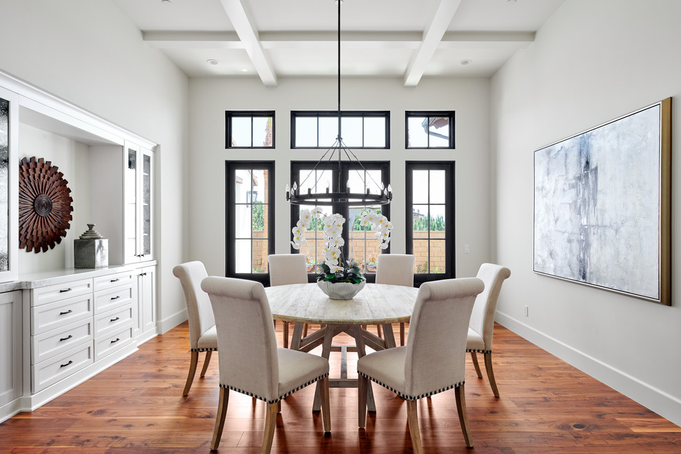 Design ideas for a mid-sized mediterranean dining room in Orange County with white walls, medium hardwood floors and brown floor.