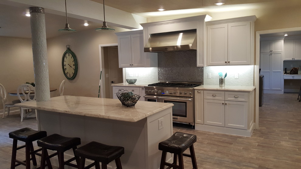 Transitional l-shaped brick floor eat-in kitchen photo in Austin with a farmhouse sink, shaker cabinets, metallic backsplash, mosaic tile backsplash, stainless steel appliances and an island