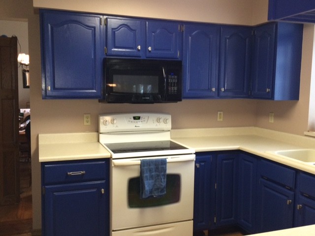 Small transitional u-shaped eat-in kitchen in Milwaukee with an integrated sink, raised-panel cabinets, blue cabinets, solid surface benchtops, medium hardwood floors, a peninsula and white appliances.