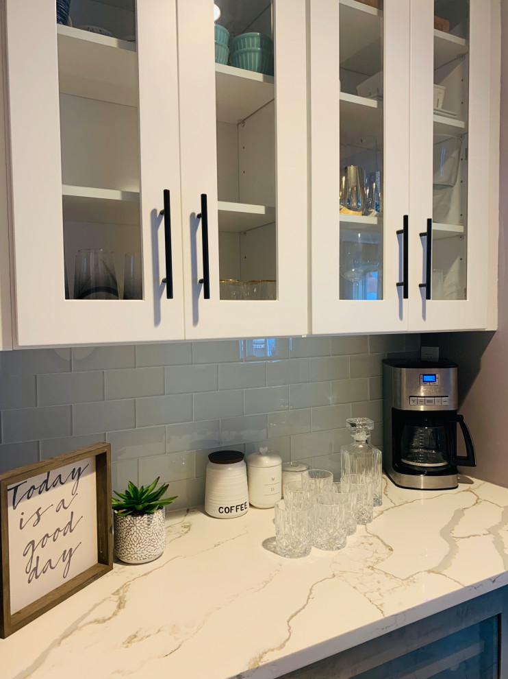 Photo of a small transitional single-wall home bar in New York with glass-front cabinets, white cabinets, marble benchtops and grey benchtop.