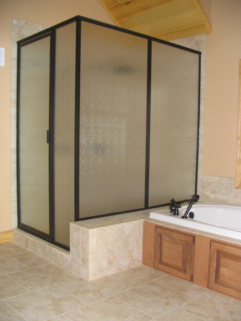Large mountain style master brown tile and ceramic tile ceramic tile drop-in bathtub photo with raised-panel cabinets, medium tone wood cabinets, a two-piece toilet, brown walls and an integrated sink