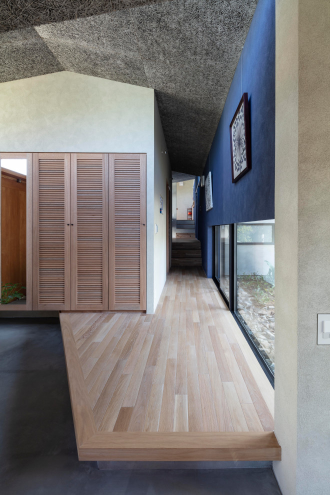 Modelo de hall gris nórdico grande con paredes azules, suelo de madera clara, puerta pivotante, puerta de madera clara, suelo beige, bandeja y machihembrado