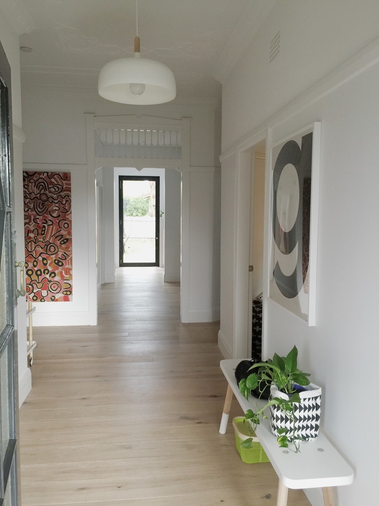Photo of a large scandinavian hallway in Sydney with white walls and light hardwood floors.