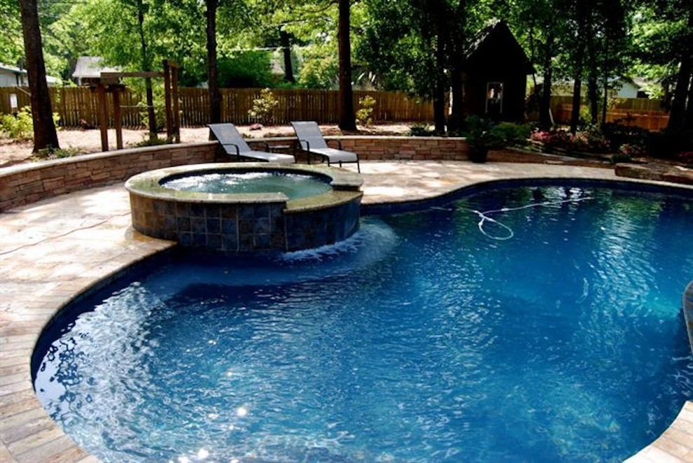 Example of a mid-sized backyard stone and rectangular natural hot tub design