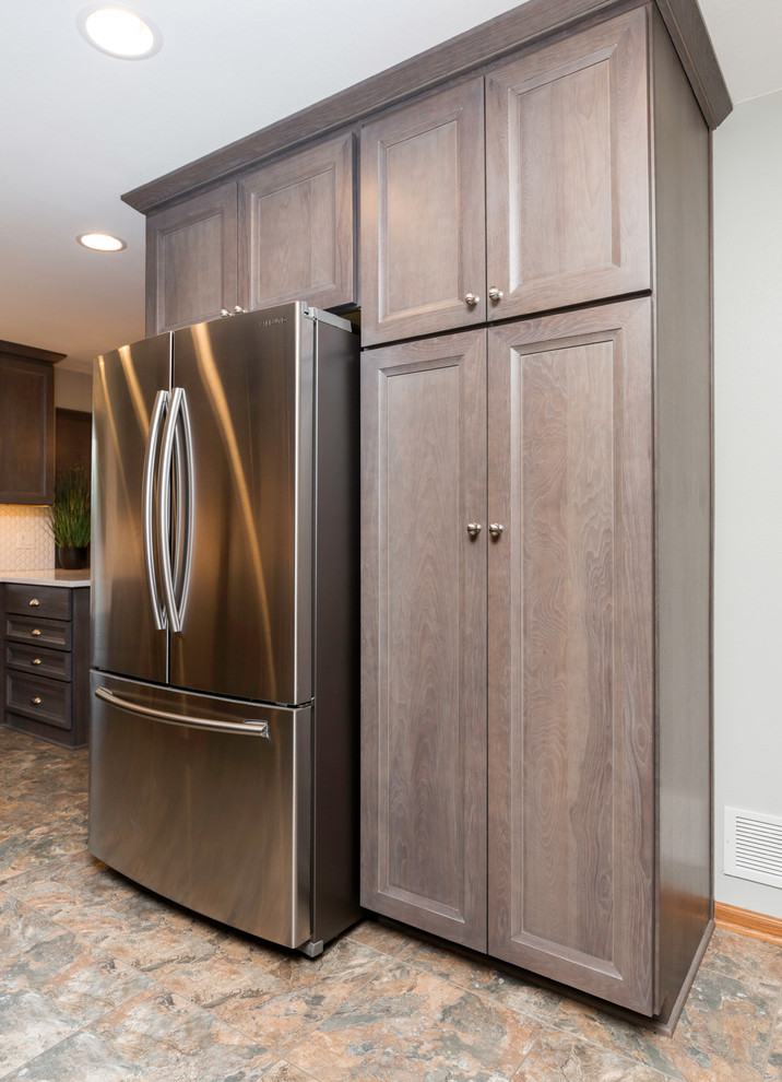Mid-sized transitional l-shaped vinyl floor and gray floor eat-in kitchen photo with a farmhouse sink, recessed-panel cabinets, gray cabinets, quartz countertops, white backsplash, ceramic backsplash, stainless steel appliances, no island and white countertops
