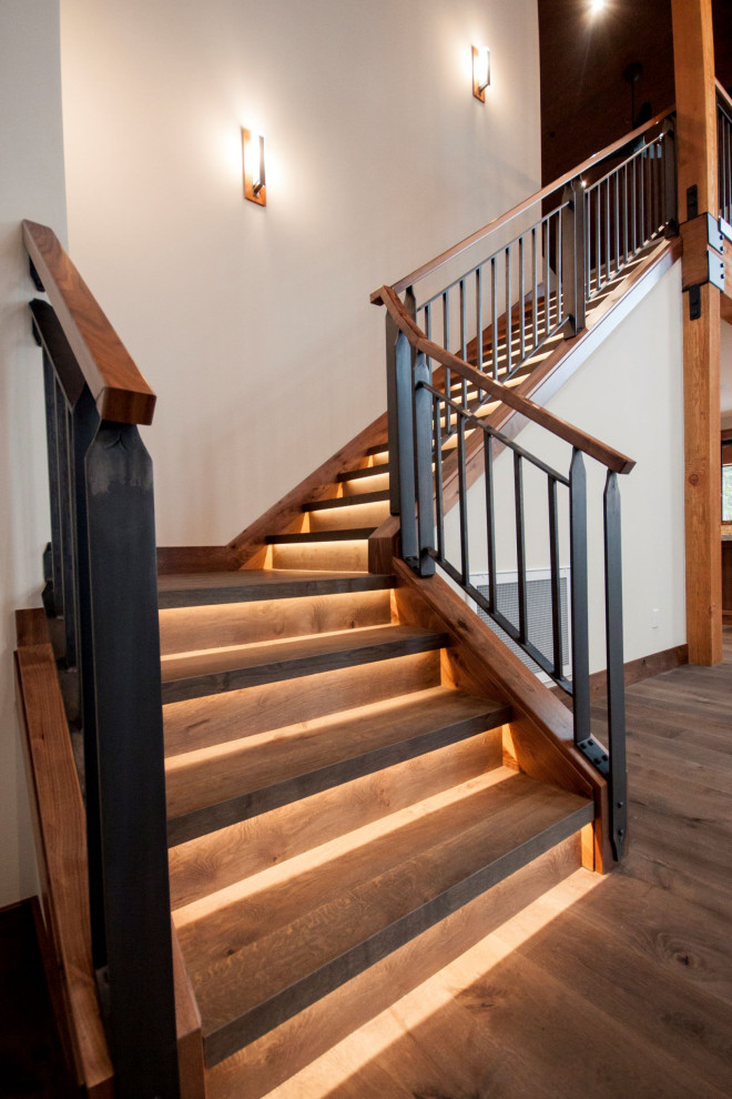На фото: угловая деревянная лестница в стиле рустика с деревянными ступенями и металлическими перилами с