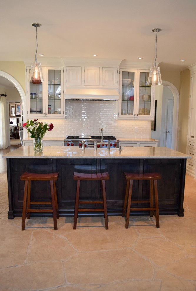Inspiration for a transitional l-shaped open plan kitchen in Denver with a farmhouse sink, raised-panel cabinets, white cabinets, white splashback, subway tile splashback, stainless steel appliances and with island.