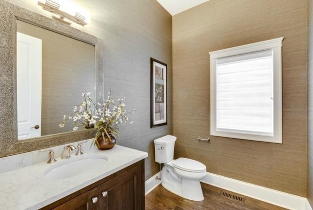 This is an example of a large traditional 3/4 bathroom in Chicago with recessed-panel cabinets, brown walls, medium hardwood floors, an undermount sink, brown cabinets, a one-piece toilet, engineered quartz benchtops, brown floor, white benchtops, a single vanity and wallpaper.