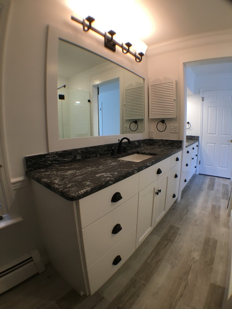 This is an example of a mid-sized modern master bathroom in DC Metro with flat-panel cabinets, white cabinets, an alcove shower, a two-piece toilet, white tile, ceramic tile, white walls, ceramic floors, an undermount sink and granite benchtops.