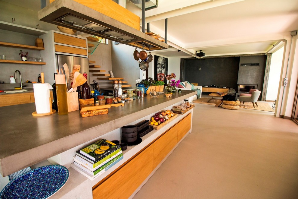 Photo of a mid-sized contemporary galley eat-in kitchen in Other with a double-bowl sink, recessed-panel cabinets, light wood cabinets, concrete benchtops, grey splashback, cement tile splashback, concrete floors, with island, grey floor and grey benchtop.