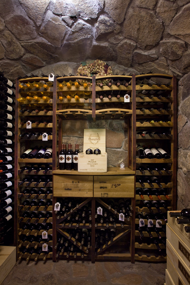 Photo of a mid-sized country wine cellar in Phoenix with limestone floors, storage racks and brown floor.