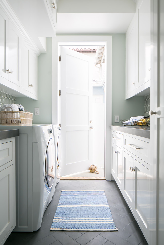 Photo of a mid-sized beach style galley dedicated laundry room in Orange County with an undermount sink, shaker cabinets, white cabinets, concrete benchtops, porcelain floors, a side-by-side washer and dryer, grey floor and grey walls.