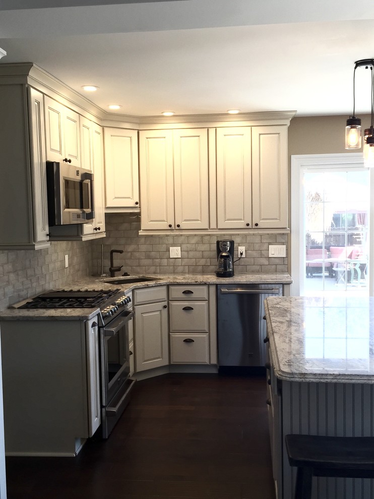 Example of a large transitional u-shaped dark wood floor and brown floor eat-in kitchen design in Atlanta with an undermount sink, raised-panel cabinets, beige cabinets, granite countertops, beige backsplash, glass tile backsplash, stainless steel appliances, an island and beige countertops