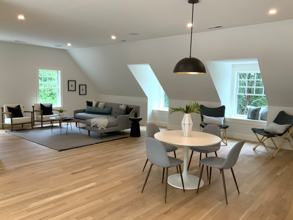 This is an example of an expansive transitional open concept family room in Boston with a game room, white walls, light hardwood floors, a concealed tv and beige floor.