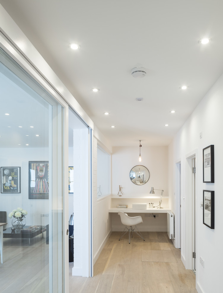 Contemporary hallway in London with white walls and light hardwood floors.