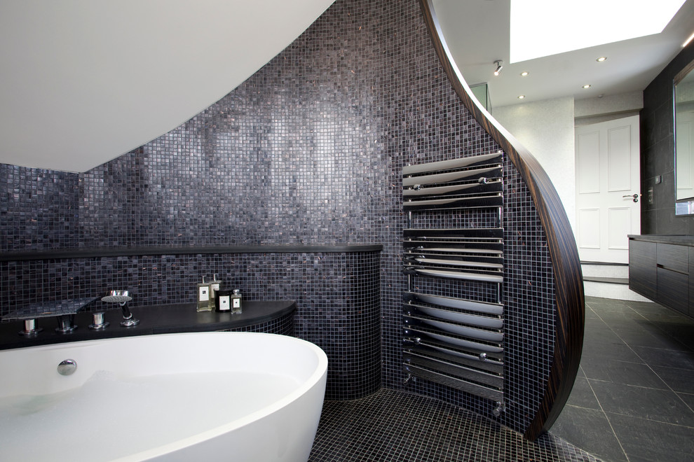 This is an example of a mid-sized contemporary master bathroom in London with a trough sink, dark wood cabinets, wood benchtops, a freestanding tub, a double shower, a one-piece toilet, black tile, ceramic tile, white walls and slate floors.