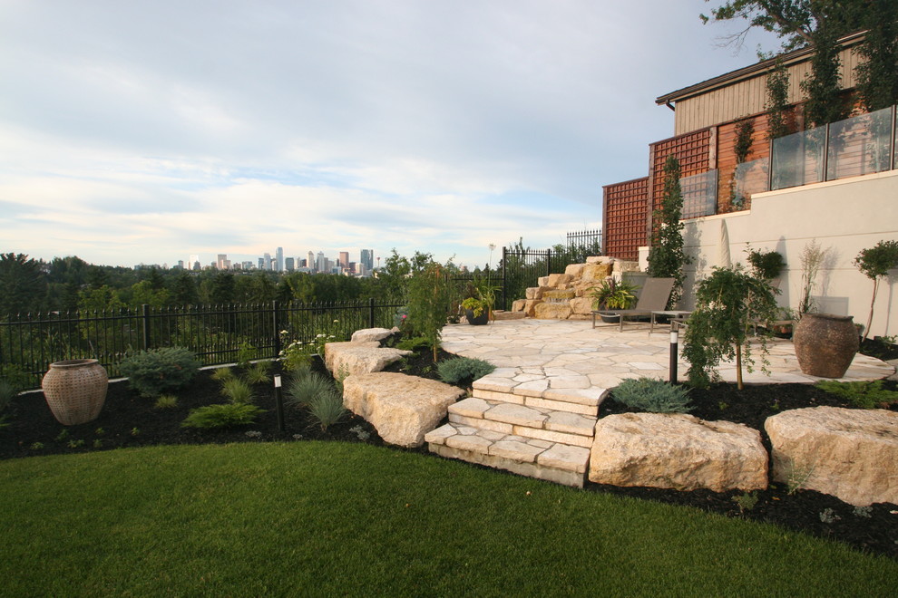 Design ideas for a mid-sized traditional backyard full sun outdoor sport court for summer in Calgary with natural stone pavers and a water feature.