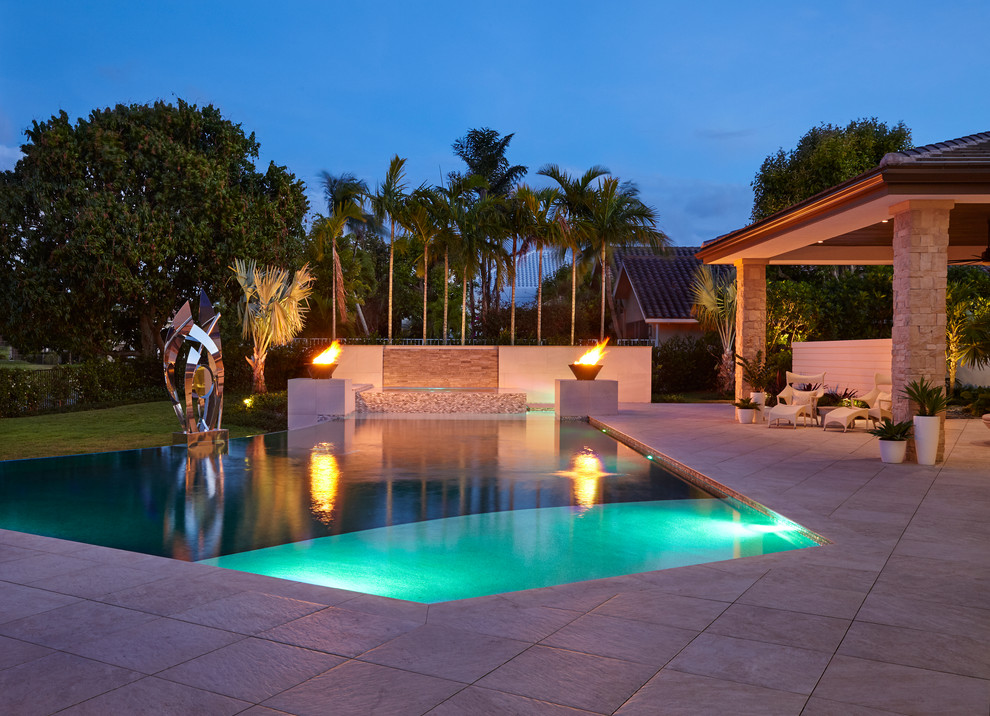 Design ideas for a contemporary backyard custom-shaped infinity pool in Miami with a hot tub.