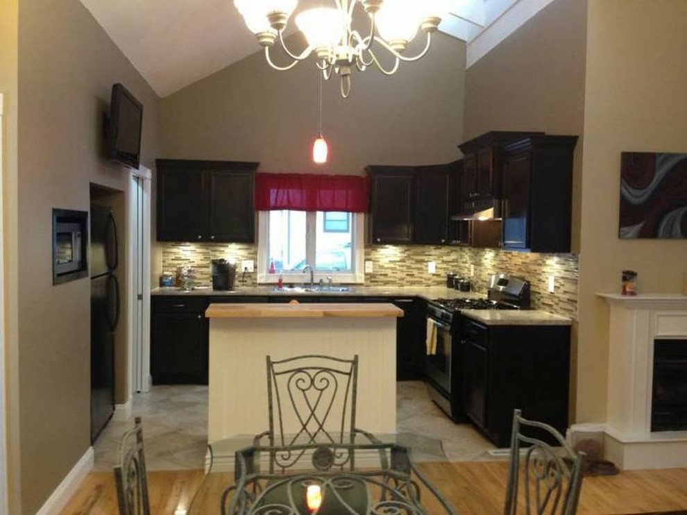 Example of a transitional ceramic tile kitchen design with a double-bowl sink, flat-panel cabinets, dark wood cabinets, wood countertops, multicolored backsplash, glass tile backsplash, stainless steel appliances and an island