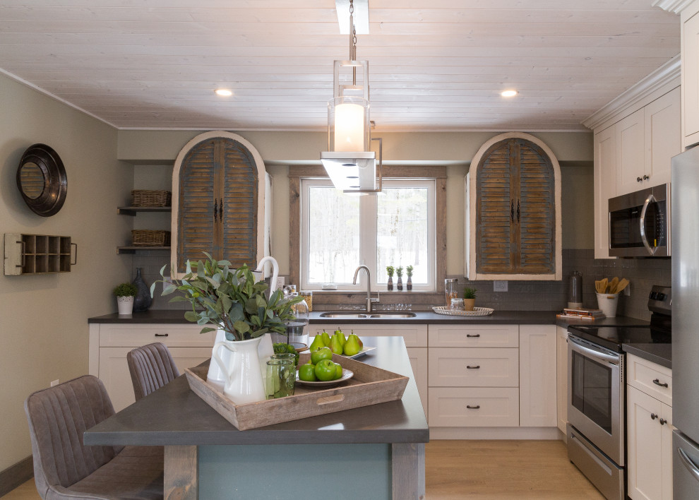 Inspiration for a mid-sized transitional l-shaped beige floor kitchen remodel in Toronto with an undermount sink, shaker cabinets, white cabinets, gray backsplash, stainless steel appliances, an island and black countertops