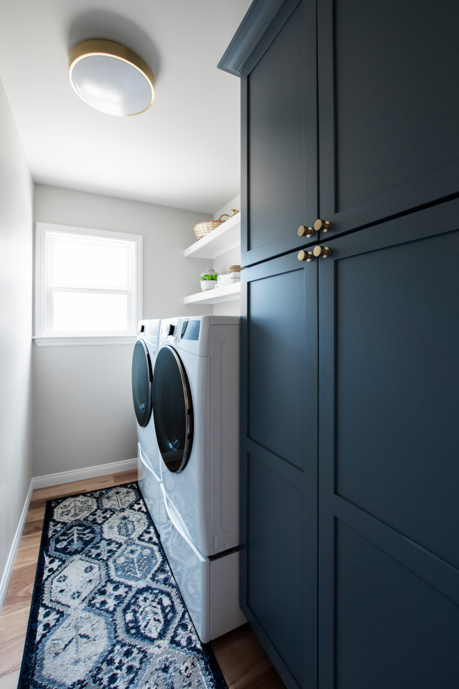 サンフランシスコにある高級な中くらいなトランジショナルスタイルのおしゃれな洗濯室 (ll型、シェーカースタイル扉のキャビネット、青いキャビネット、グレーの壁、無垢フローリング、左右配置の洗濯機・乾燥機) の写真