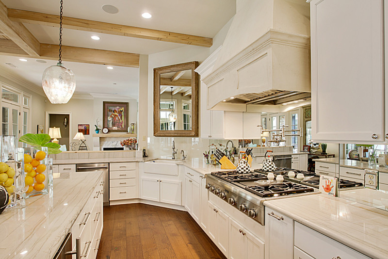 Inspiration for a large country u-shaped open plan kitchen in New Orleans with a farmhouse sink, shaker cabinets, white cabinets, marble benchtops, metallic splashback, mirror splashback, stainless steel appliances, medium hardwood floors and with island.