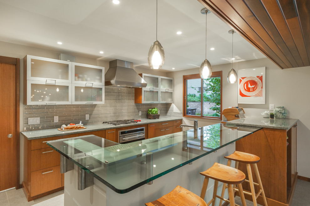 Design ideas for a mid-sized midcentury galley eat-in kitchen in Detroit with flat-panel cabinets, granite benchtops, grey splashback, glass tile splashback, stainless steel appliances and a peninsula.
