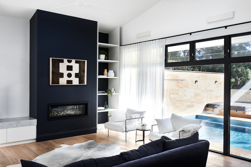 Design ideas for a large contemporary open concept living room in Sydney with blue walls, light hardwood floors, a standard fireplace and a plaster fireplace surround.