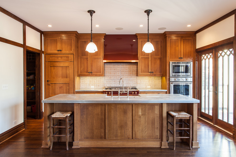 This is an example of a mid-sized traditional single-wall separate kitchen in Chicago with a farmhouse sink, recessed-panel cabinets, medium wood cabinets, zinc benchtops, multi-coloured splashback, ceramic splashback, panelled appliances, dark hardwood floors, with island and brown floor.