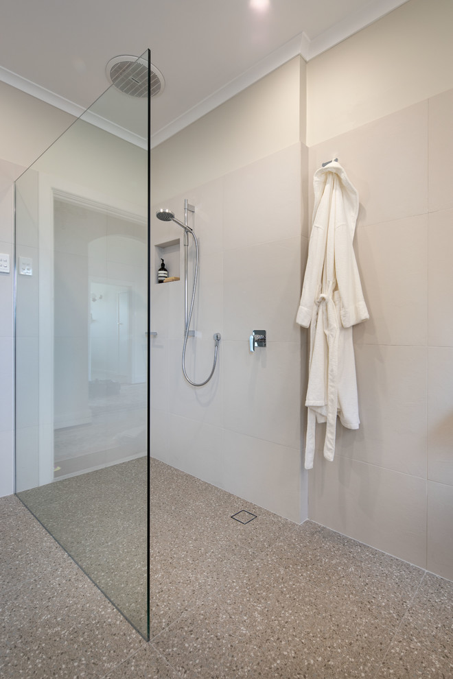 Design ideas for a mid-sized modern 3/4 bathroom in Melbourne with flat-panel cabinets, beige cabinets, a drop-in tub, a curbless shower, a one-piece toilet, beige tile, porcelain tile, beige walls, porcelain floors, a drop-in sink, quartzite benchtops, multi-coloured floor, an open shower and white benchtops.
