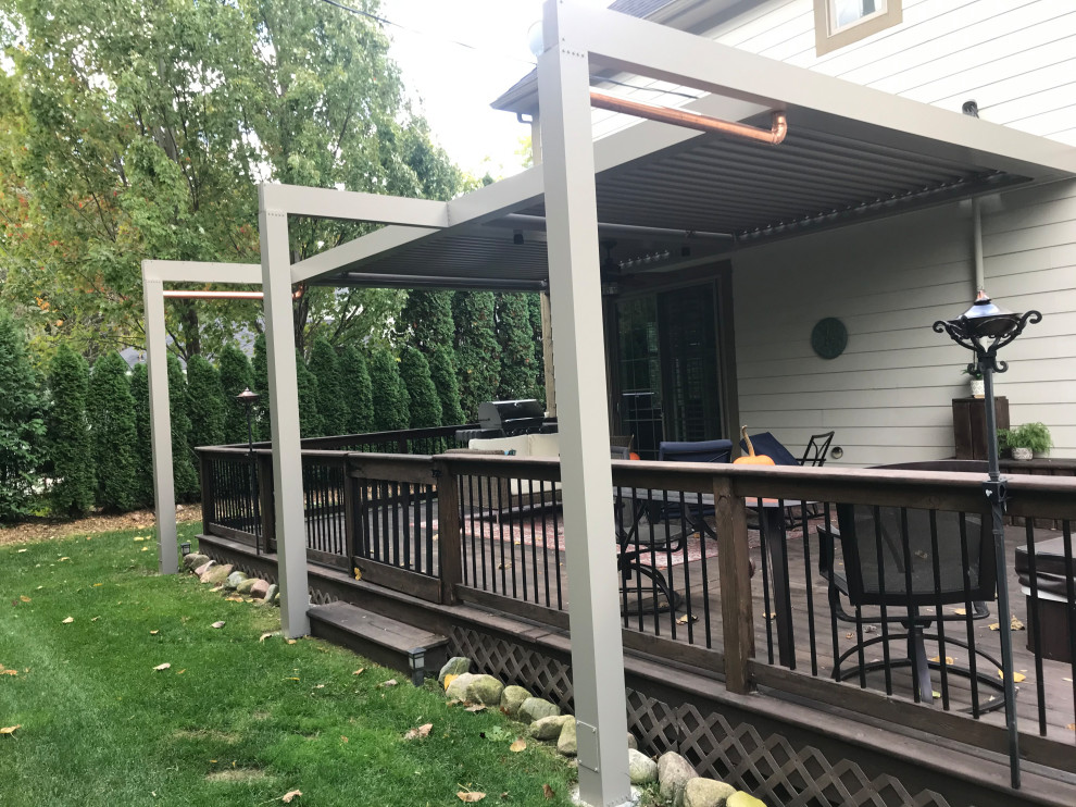 Photo of a mid-sized modern backyard and ground level deck in Detroit with a pergola and mixed railing.