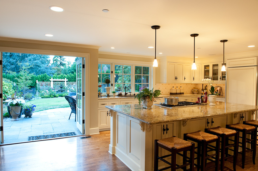 Photo of a large traditional l-shaped open plan kitchen in Seattle with recessed-panel cabinets, beige cabinets, beige splashback, ceramic splashback, panelled appliances, with island and dark hardwood floors.