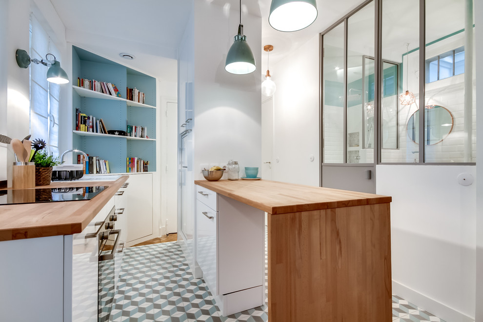 Small scandinavian galley open plan kitchen in Paris with a single-bowl sink, flat-panel cabinets, white cabinets, wood benchtops, stainless steel appliances, cement tiles and with island.