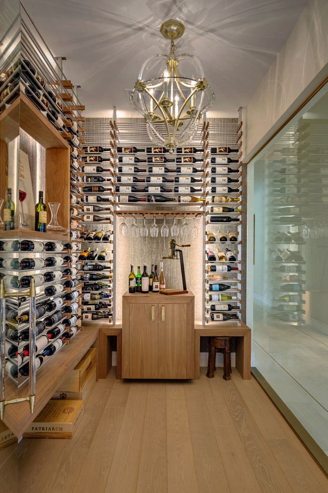 Photo of a mid-sized contemporary wine cellar in Phoenix with light hardwood floors, display racks and beige floor.