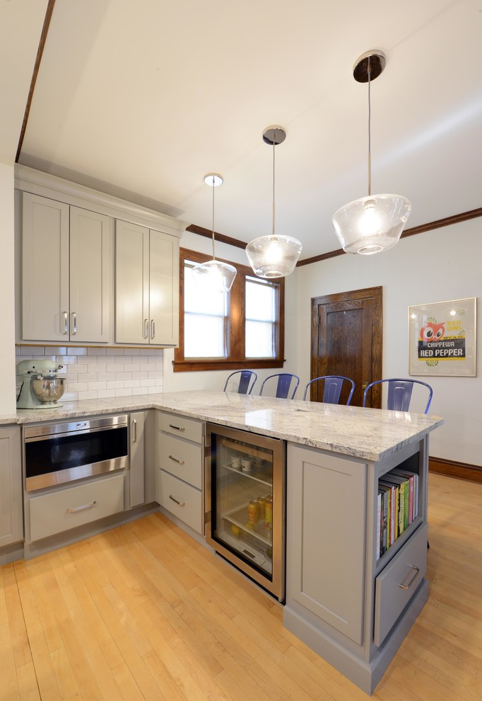 Inspiration for a mid-sized transitional light wood floor and brown floor enclosed kitchen remodel with a farmhouse sink, shaker cabinets, gray cabinets, wood countertops, white backsplash, porcelain backsplash, stainless steel appliances, an island and brown countertops