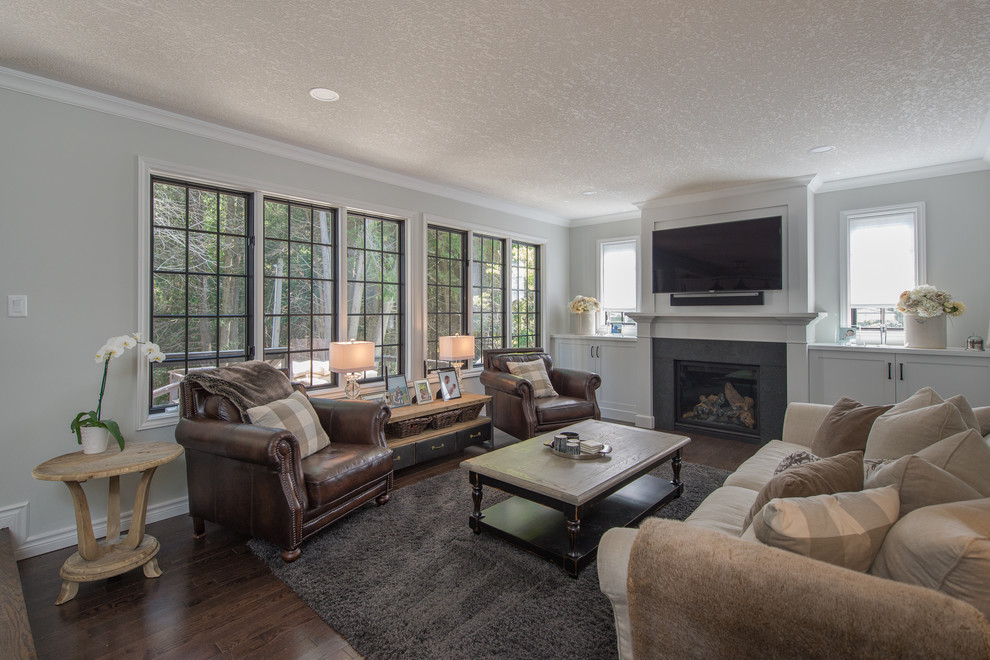 Mid-sized transitional open concept family room in Toronto with dark hardwood floors, a standard fireplace, white walls, a wood fireplace surround, a wall-mounted tv and brown floor.