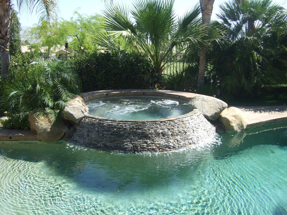 Inspiration for a small tropical backyard round natural pool in Los Angeles with a hot tub and decking.