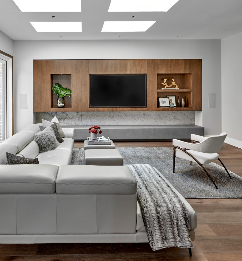 Design ideas for a contemporary family room in Chicago with grey walls, medium hardwood floors, a wall-mounted tv and brown floor.