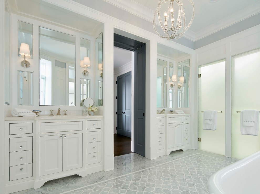 This is an example of a large transitional master bathroom in Chicago with recessed-panel cabinets, white cabinets, a freestanding tub, a two-piece toilet, gray tile, stone tile, white walls, an undermount sink and mosaic tile floors.